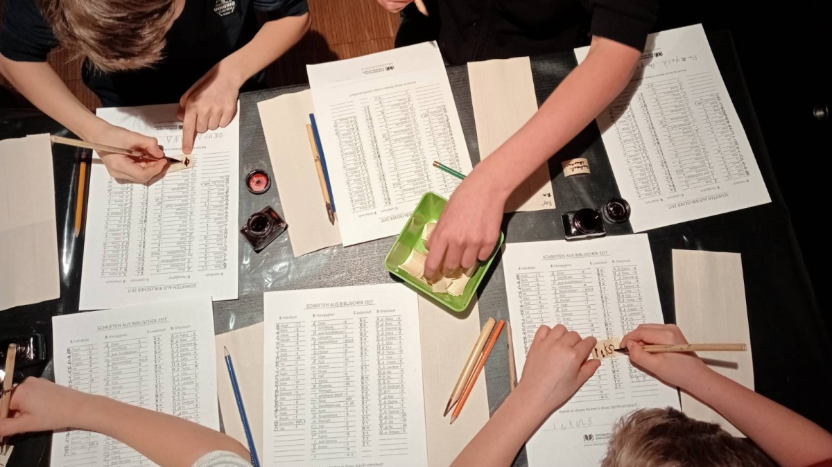 Bei der Schreibwerkstatt lernen die Jugendlichen wie sich das Schreiben auf Papyrus und Pergament anfühlt. Die Paulausfreaks bei der Schreibwerkstatt